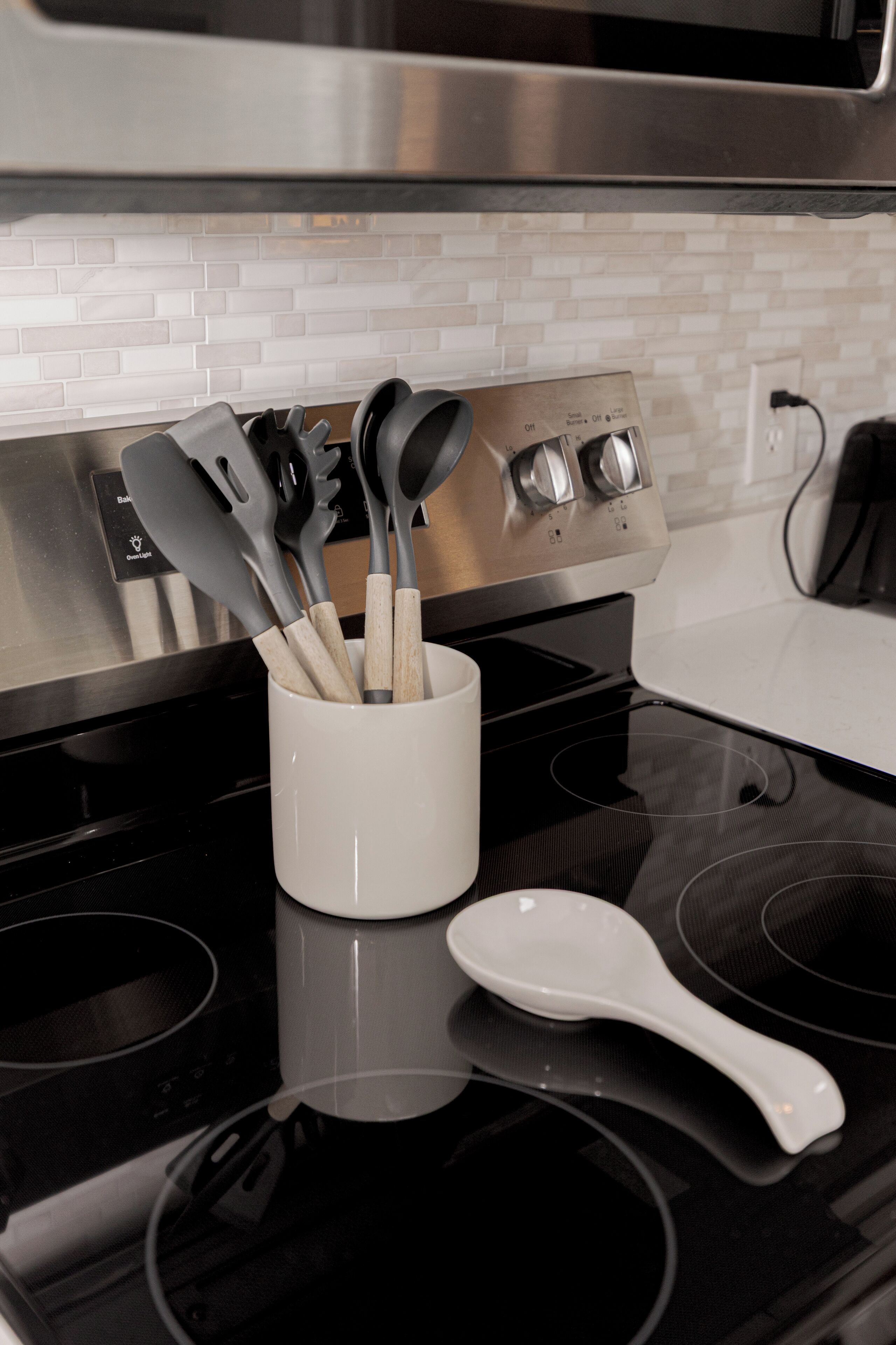 Eine Küche mit einer weißen Tasse, die Küchenutensilien, einen weißen Löffel und einen Edelstahlbackofen enthält.