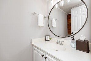 A bathroom with a white sink, a large mirror, and a towel rack. - Convenient Stay | 3BR | Fenced Yard | Near RAFB (Warner Robins)