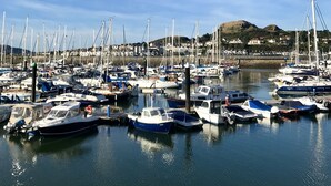 A marina with numerous boats docked, a clear sky, and a hilly landscape in the background. - Isfyn, Boutique style cottage with stunning views in Llandudno.  (Penrhyn-side)
