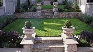 A well-maintained garden with a stone staircase leading to a lawn, surrounded by various plants and flowers. - Isfyn, Boutique style cottage with stunning views in Llandudno.  (Penrhyn-side)