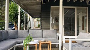 A modern outdoor seating area with a curved grey sofa, a small round table, and a white chair. - The Birkdale by Ready Set Stay- heated pool, WIFI, amazing and modern (Sunset Strip)