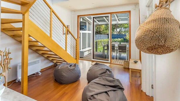 A modern interior with a wooden staircase, large windows, and a hanging light fixture. - The Birkdale by Ready Set Stay- heated pool, WIFI, amazing and modern (Sunset Strip)