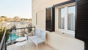 A balcony with a pool, a sofa, and two tables. - Cala Monaci Apartment (Favignana)
