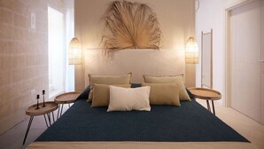 A modern bedroom with a large bed, two bedside tables, and a decorative wall piece. - Cala Monaci Apartment (Favignana)