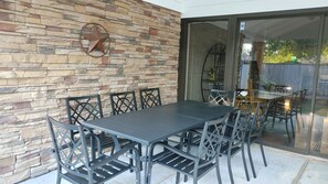 An outdoor patio with a stone wall, a metal table, and chairs. - Mid Century Modern Nights Dream (Houston)