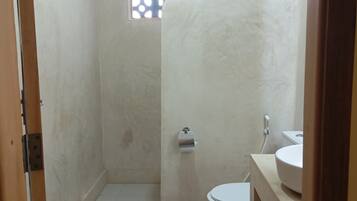 A small, compact bathroom with a shower, toilet, and sink.