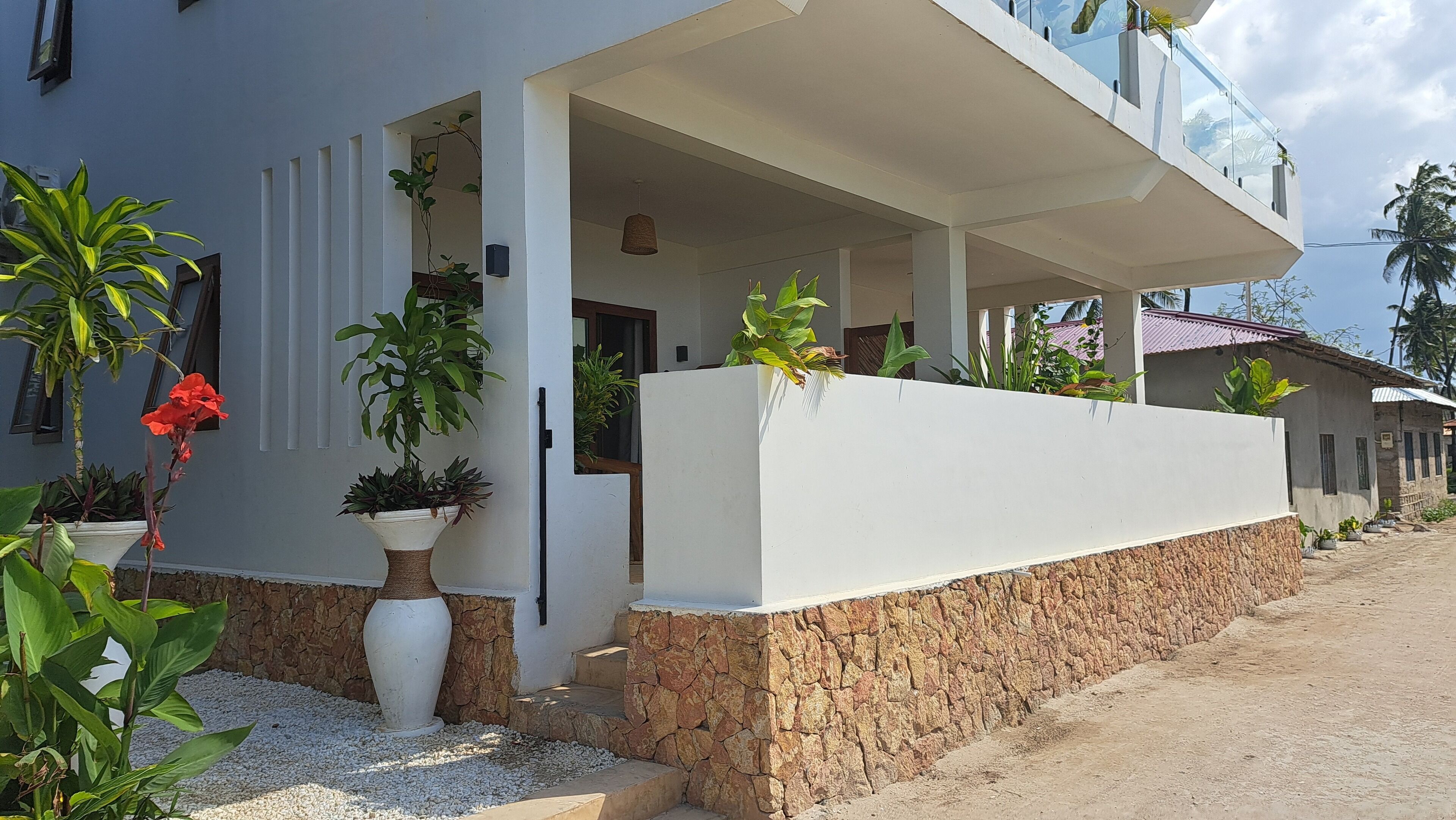 A modern building with a white exterior, a stone base, and a covered entrance.