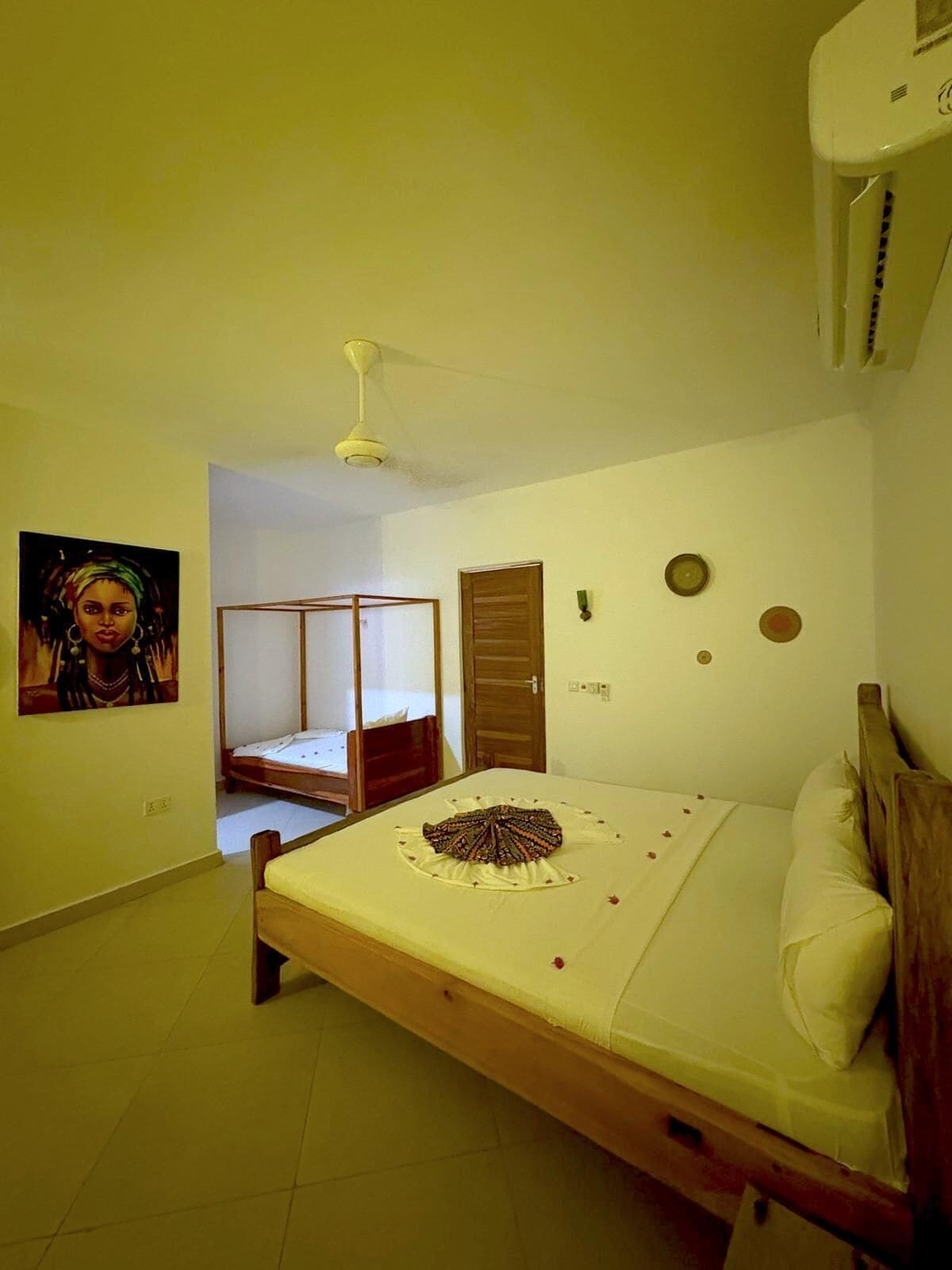 A bedroom with a single bed, a wooden wardrobe, a ceiling fan, and a wall-mounted air conditioner.