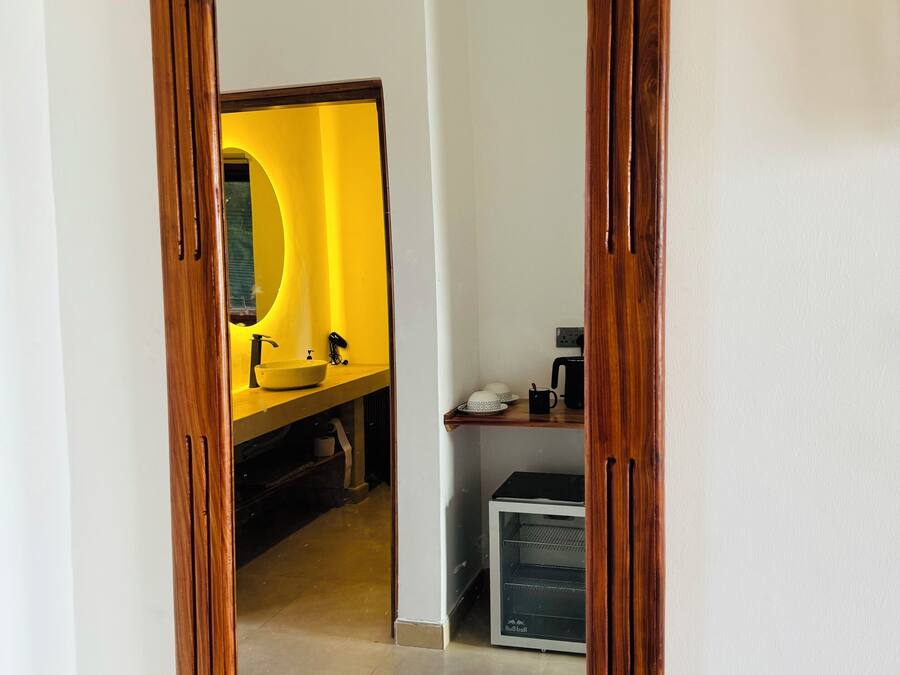 Ein Spiegel mit Holzrahmen, der ein Badezimmer mit einem gelben Waschbecken und einem schwarzen Schrank spiegelt.