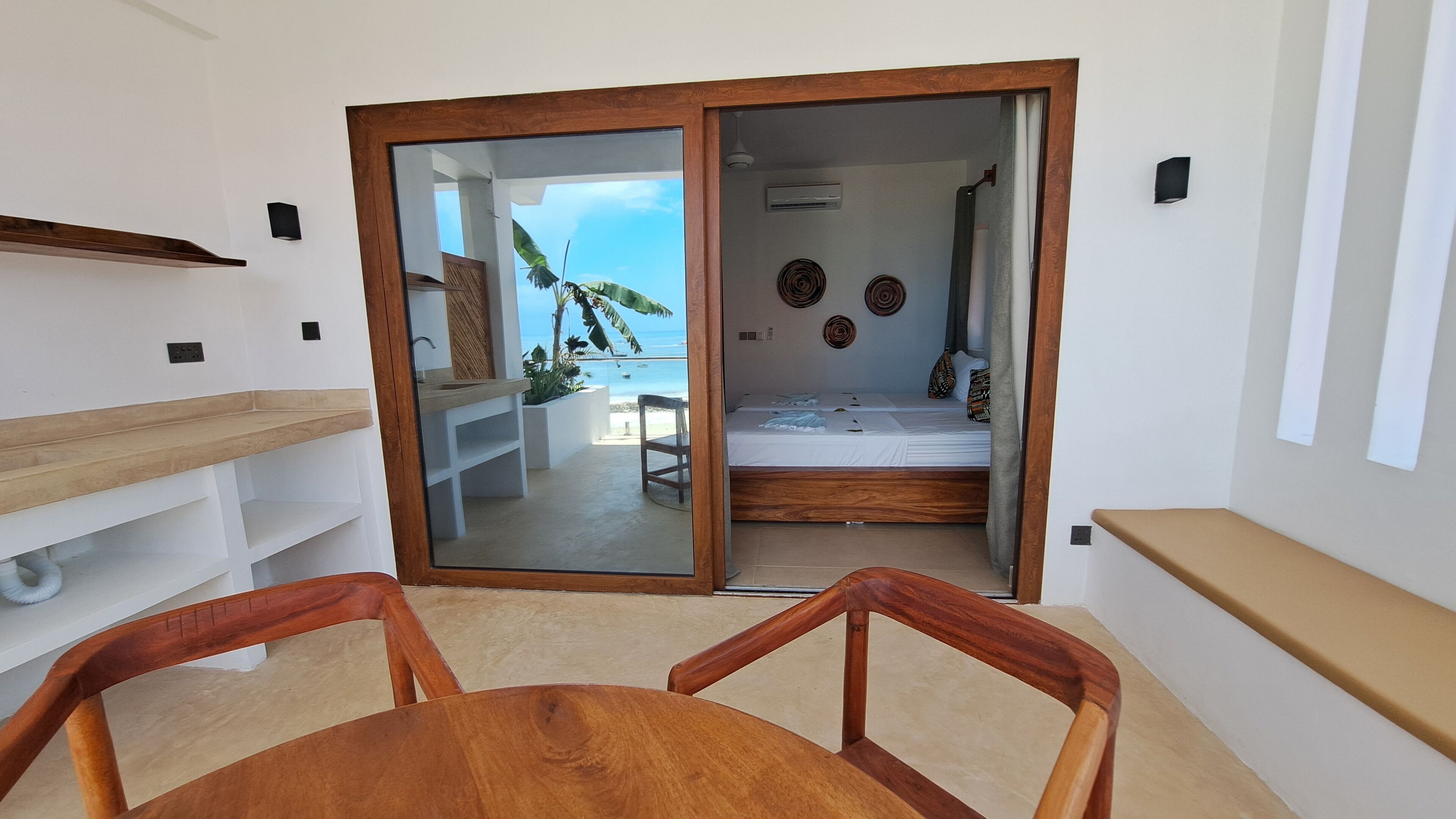 A room with a sliding glass door leading to a balcony with a view of the sea.