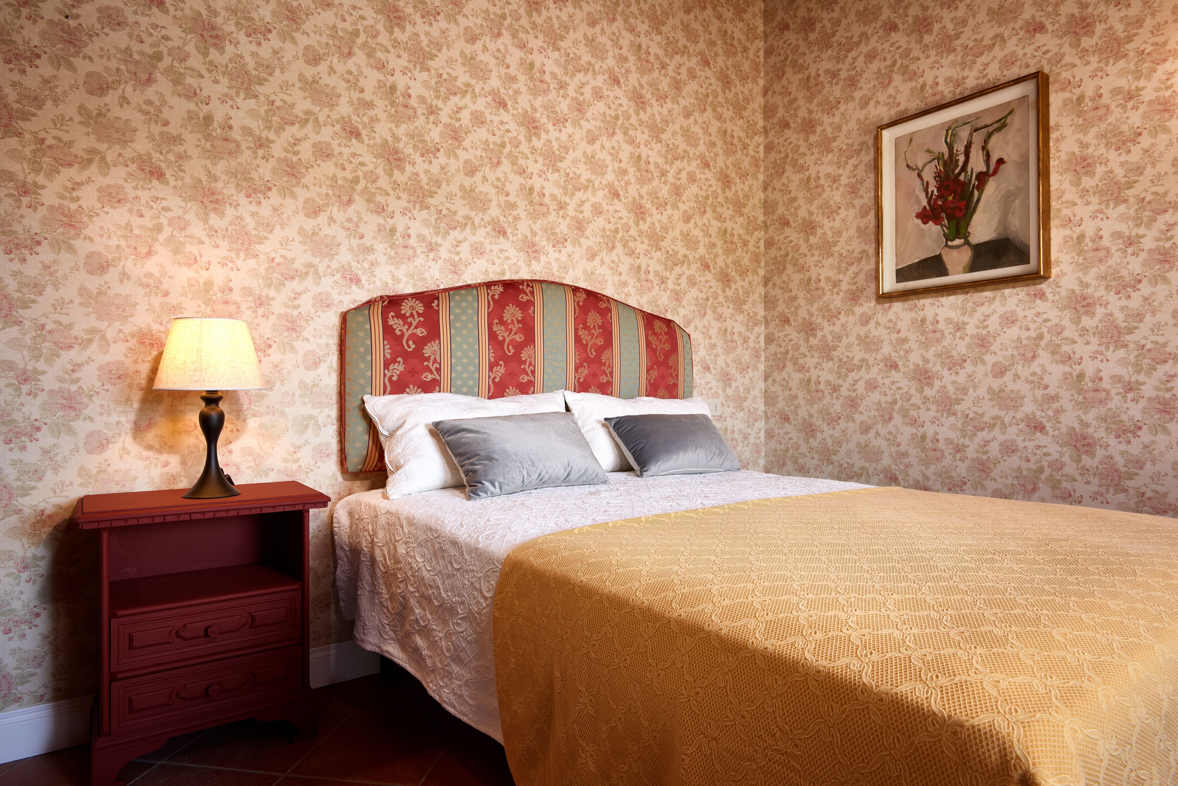 Une chambre à coucher avec un lit, une table de chevet, une lampe et un tableau encadré au mur.