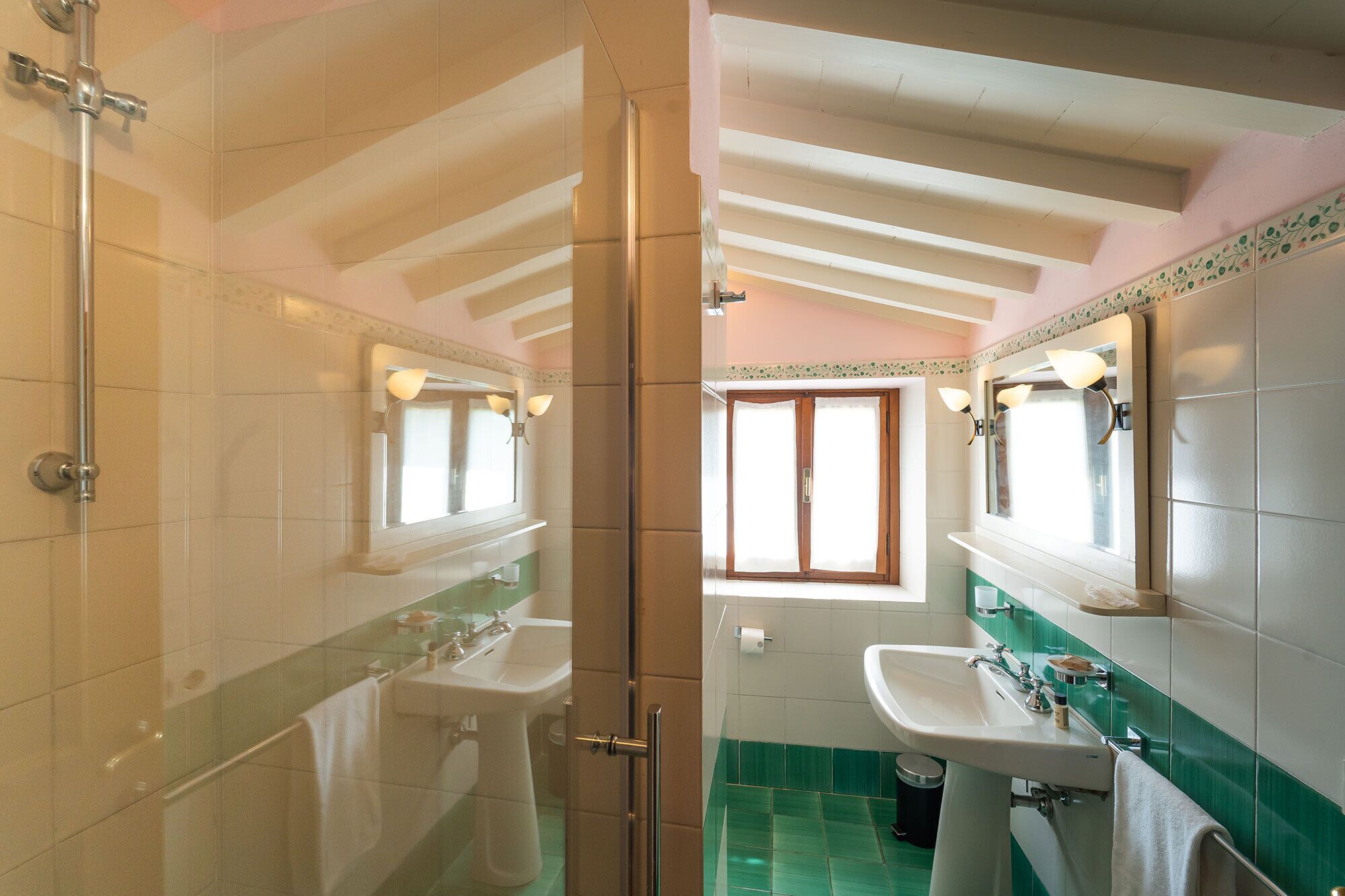 A bathroom with two sinks, a shower, and a window.