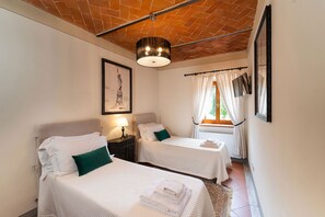 A hotel room with two beds, a ceiling with exposed brick, a framed picture on the wall, and a window with curtains. - Agriturismo Torreghiotta (Pistoia)
