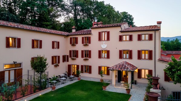A building with multiple windows and a courtyard with outdoor seating. - Agriturismo Torreghiotta (Pistoia)