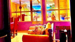 Una habitación con sofá, una silla y una mesa. Cuenta con ventanas amplias de varios paneles.
