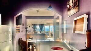 Una cocina con una isla central, un comedor con sillas y vistas a través de un arco abierto.