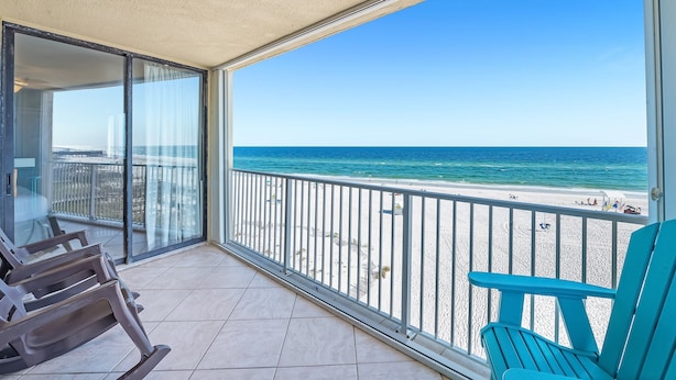 Ein Balkon mit Blick auf den Strand, eine Glastür und zwei Stühle.