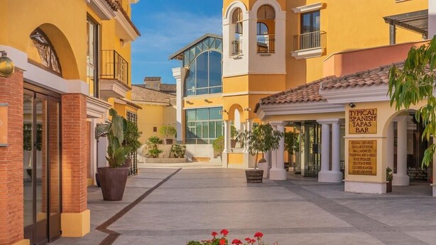 A courtyard with yellow buildings, a bar, and potted plants. - Beautiful apartment at La Torre Golf Resort TA211LT (Torre-Pacheco)