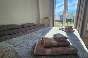 Ett hotellrum med en stor säng, en mindre säng och utsikt över omgivningarna genom fönstret.