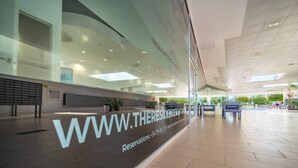 A modern hotel lobby with a glass facade, a large digital display, and a seating area. - Beautiful apartment at La Torre Golf Resort TA211LT (Torre-Pacheco)