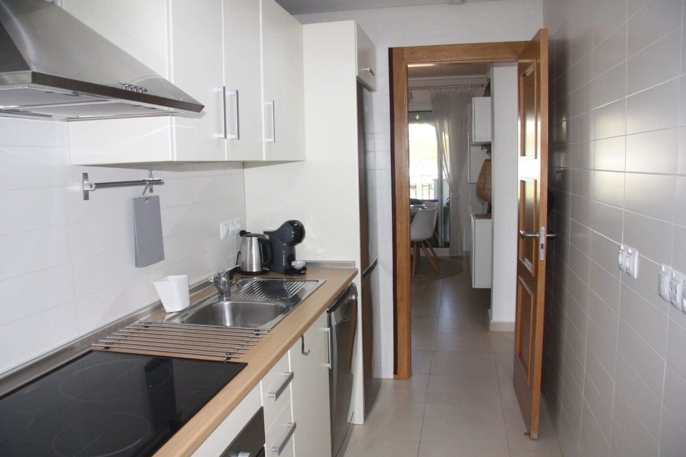 A modern kitchen with a stainless steel sink, a kettle, and a coffee maker.