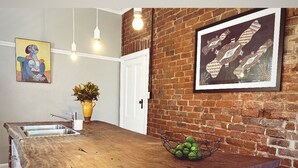 A kitchen with a wooden countertop, a sink, a potted plant, hanging lights, and a brick wall. - The BnB filled to the brim with character and charm! (Dubbo)