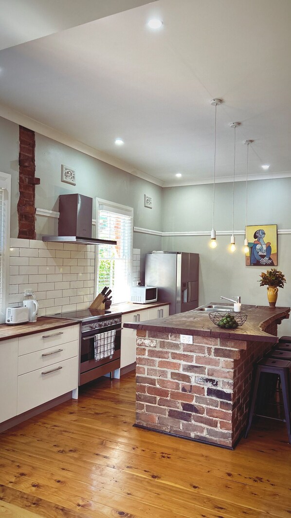 A modern kitchen with white cabinets, a brick island, and a stainless steel refrigerator.
