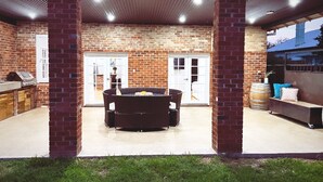 An outdoor patio area with a brick wall, a covered seating area, and a barbecue grill. - The BnB filled to the brim with character and charm! (Dubbo)
