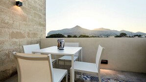 A balcony with a white table and chairs, a can of paint, and a view of distant mountains. - Appartamento Cala Rotonda (Favignana)