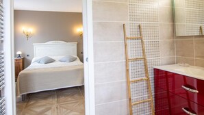 A bedroom with a bed, bedside lamps, a ladder, and a red cabinet.