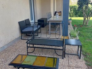An outdoor seating area with a metal bench, a small table, and a chair. - Peaceful house with terrace and garden near prehistoric sites (Le Bugue)