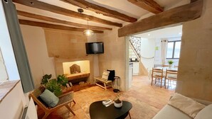 Ein gemütliches Wohnzimmer mit Kamin, einer Couch, einem Couchtisch und einem Essbereich. Eine Treppe führt in einen anderen Raum.