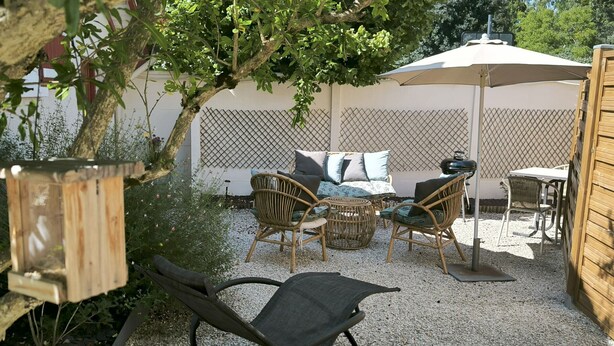 A patio area with wicker furniture, a small table, and a chair. - Charming Riverside Cottage Near Montargis with Nature & City Access (Montargis)