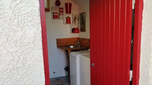A compact kitchen with a washing machine, a sink, and a small countertop. - Charming Riverside Cottage Near Montargis with Nature & City Access (Montargis)