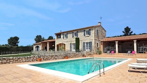 Un edificio de piedra con piscina, mobiliario exterior y un muro de piedra.