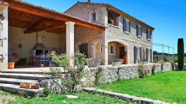 Una casa de piedra con porche cubierto y un jardín adosado de piedra.