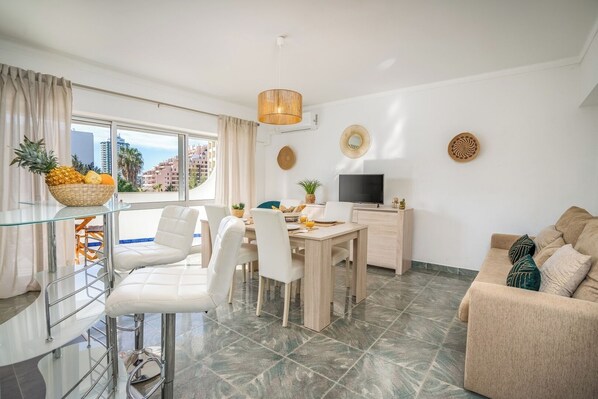 Relax in this stylish living room with a glass dining table, comfortable sofa, and flat-screen TV.