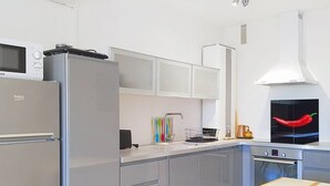 Een moderne keuken met een koelkast, magnetron, oven en een opvallende chilipeper decoratie.
