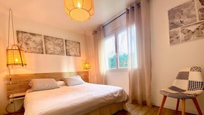 Un dormitori amb un llit de fusta, dues làmpades de nit, una finestra amb cortines i una cadira amb dibuixos de quadres.