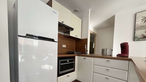 A modern kitchen with a white refrigerator, oven, and microwave, wooden cabinets, and a countertop with a toaster and coffee maker.