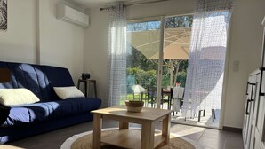 A living room with a blue sofa, a wooden coffee table, and a view of an outdoor patio area.