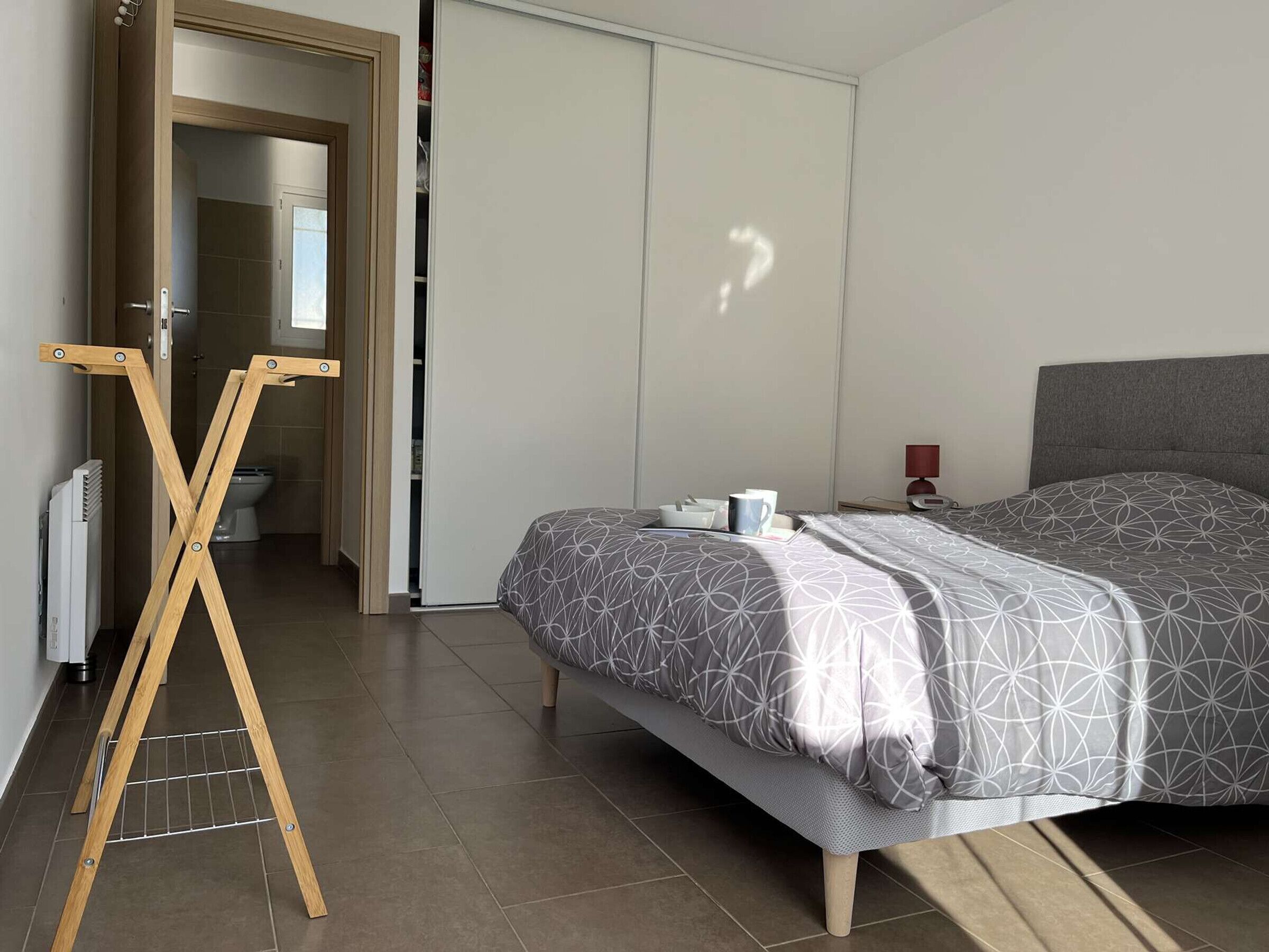 Ein modernes Schlafzimmer mit einem Bett, einem Staffelei aus Holz und einem Kleiderschrank.