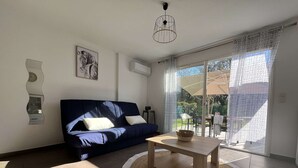 A modern living room with a blue sofa, a wooden coffee table, and a large glass door leading to an outdoor area.