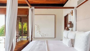 A bedroom with a large bed, white bedding, a wooden headboard, a framed artwork on the wall, and a view of greenery outside. - Casa Colmena: Luxury 6BR Villa w/ Infinity Pool (Corral del Risco)