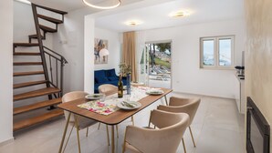A dining area with a wooden table, chairs, and a staircase. - Emerald Eco Villa (Povlja)