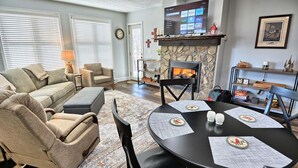 Een woonkamer met een open haard, een televisie en een eettafel gedekt voor twee personen.