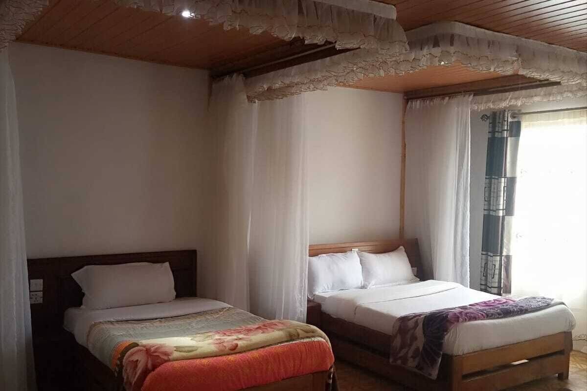 A room with two beds, a wooden ceiling, and a patterned floor.