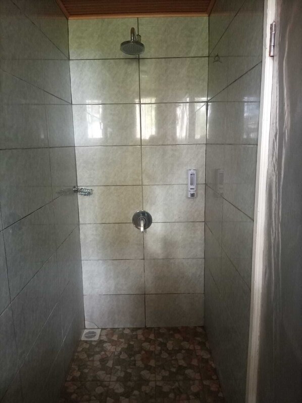 A shower stall with a handheld showerhead, a control panel, and a tiled floor. - Deep Sea Resort Kitale (Kitale)