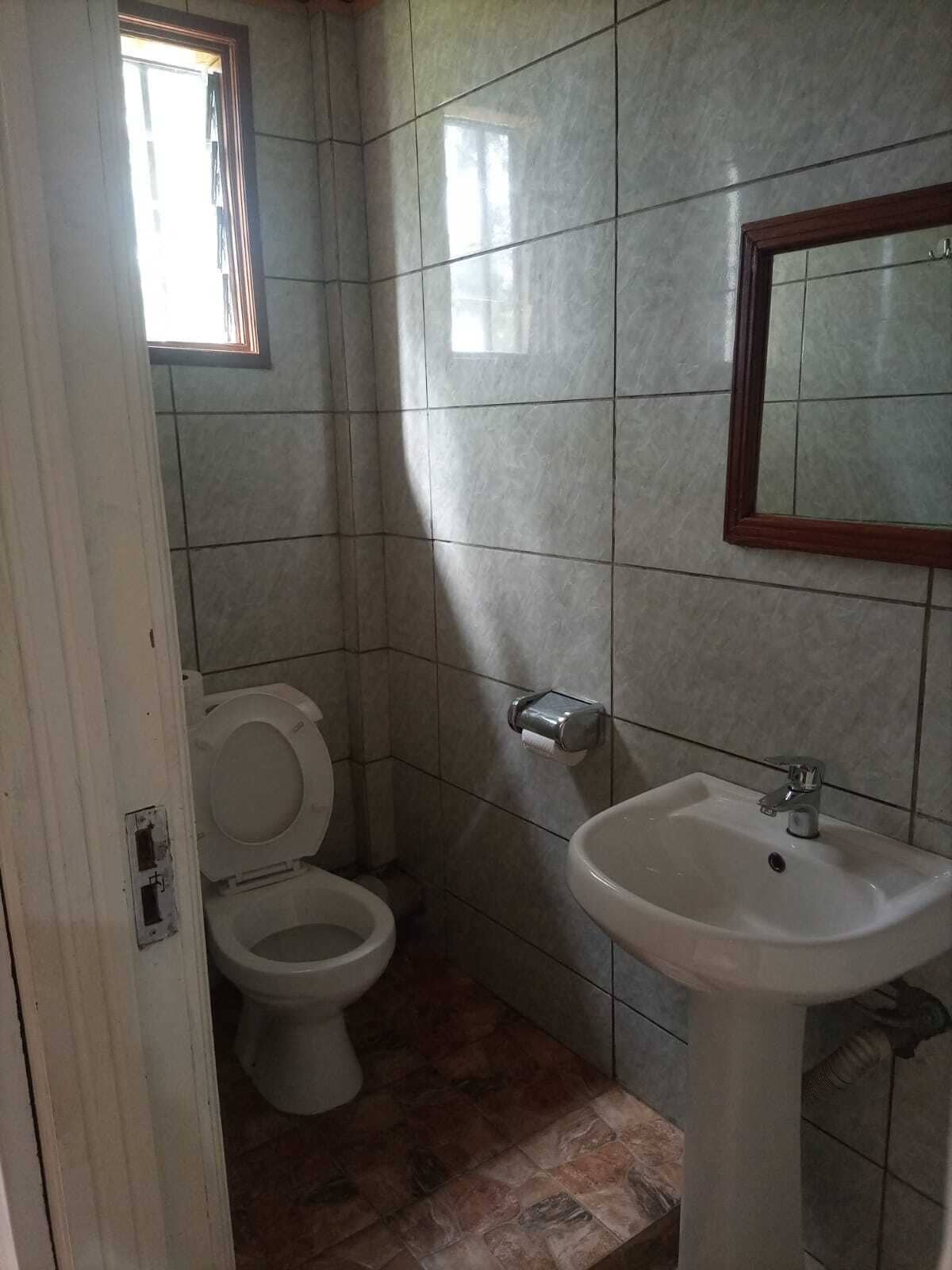 A bathroom with a toilet, sink, and tiled walls.