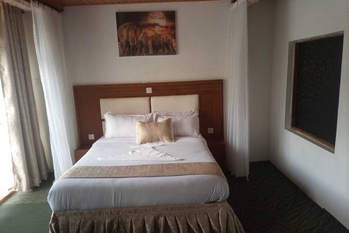 A neatly made bed with a wooden headboard, white bedding, and a decorative throw.